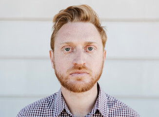 Portrait of serious ginger young adult man looking at camera outdoors