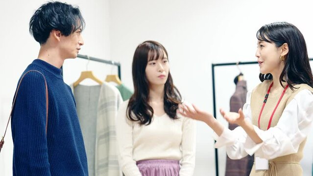 アパレルショップで接客する店員と試着するカップル客