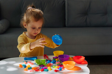 A little girl playing with Colors sorter toy on the table in children room. Educational games for Rainbow Colors sorting. Learning through play. Developing Montessori toddlers activities.