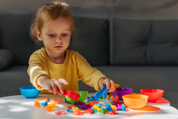 A little girl playing with Colors sorter toy on the table in children room. Educational games for Rainbow Colors sorting. Learning through play. Developing Montessori toddlers activities.