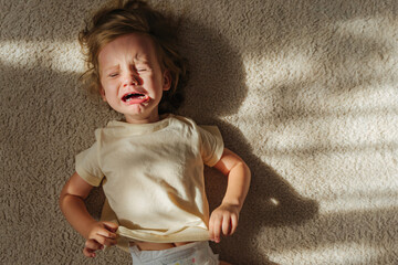 Toddler cries and is naughty lying on the floor  in the nursery. Children's tantrums, tears and...