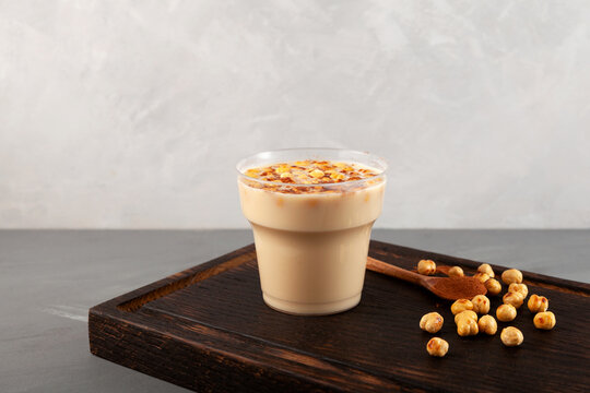 Boza or Bosa in disposable plastic take away cup on wooden board. Turkish fermented drink with roasted chickpea