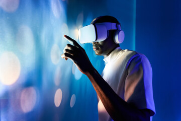Serious black man touching large screen while exploring virtual reality in modern headset