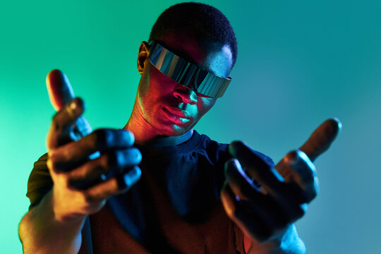 Confident black man in futuristic headset reaching out hand to camera - Powered by Adobe