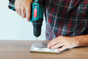 Drilling a Hard Disk Drive to Destroy Evidence Data close up.Cropped image of hand drilling on hard...