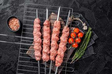 Raw Shish kebab from mince lamb and beef meat, turkish adana kebab on Skewers. Black background. Top view
