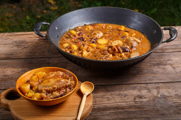 Cheolnt in a large frying pan and a plate on a wooden board on the table next to a spoon.