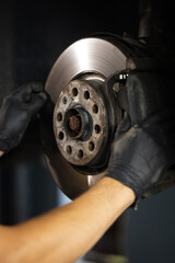 Mechanic at service station checks the brake and steering systems. Strong man checks for wear in...