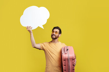 Positive male tourist with travel suitcases holding empty speech bubble above his head, copy space,...