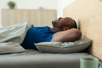 Black Guy Lying In Bed Holding Hands Behind Head Indoor