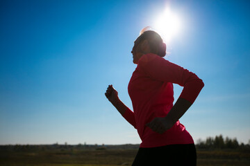 Fototapeta na wymiar Silhouette of a woman running against the blue sky.
