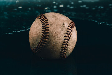 Retro baseball used in game with water background for rain delay or game concept.