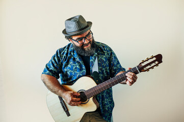 Happy bearded man playing acoustic guitar on pink background.