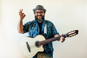 Happy bearded man playing acoustic guitar on pink background.