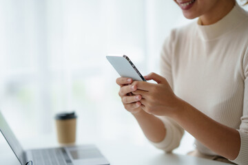 Close-up of a woman using a smartphone to work on various application including mobile transaction to send messages, LINE, and various business information sent via social media.