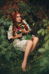Red-haired girl with horns in a white vyshyvanka in the park