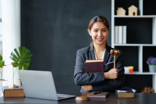 Beautiful Asian Woman Lawyer Sitting At A Table Smiling Happy With A Laptop Computer With Law Books Hammer And Scales Hammer And Scale.