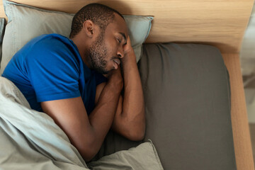 Fototapeta premium High Angle Of Sleeping Black Guy Napping In Bed Indoors
