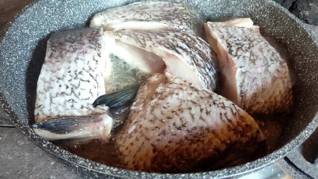 Fish meat placed into pot with hot oil. Cooking fish in hot oil pan.