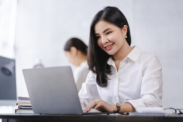 Smiling Asian businesswoman working on laptop in modern office Accountant Concept Finance Expert Analyze Business Report Graph financial chart financial chart corporate economy Banking Market Research