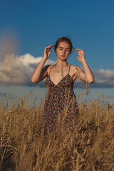 A young girl dances in a wheat field against a blue sky.