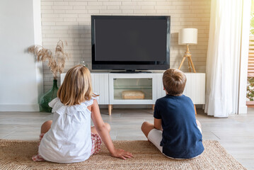Two children sitting on the living room floor watching television. Mock up for inserting images in...