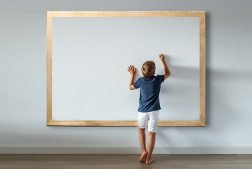 Caucasian boy standing writing messages and texts on a large white board. Mockup for inserting...