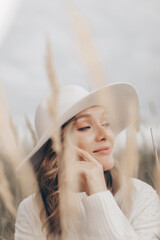 blonde girl in a white hat walks along the seashore on an autumn day - 527368097