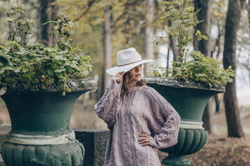 blonde in a white hat walks in the old park on an autumn day