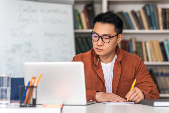 Korean Middle Aged Teacher Using Laptop Taking Notes In Classroom