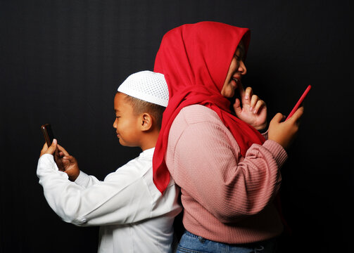 A child and his mother are playing on each other's cellphone isolated on black background.