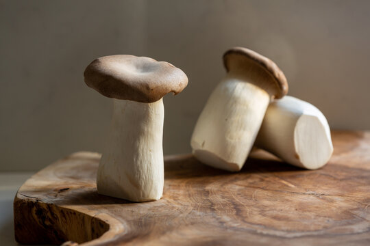 A trio of king oyster mushrooms shot in natural morning light on a wooden baord