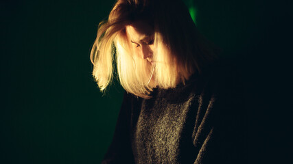 Blonde girl in a room near the wall in the rays of light