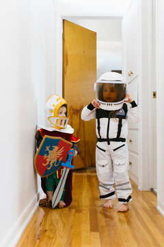 Toddler boy (2-3) in knight costume and girl (2-3) in astronaut costume playing at home
