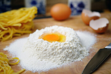 On the table is flour with an egg for Italian pasta. Homemade food. Rustic.