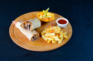 Meat doner kebab on lavash bread. Traditional Turkish cuisine delicacies on wooden presentation board on black background. Selective focus.

