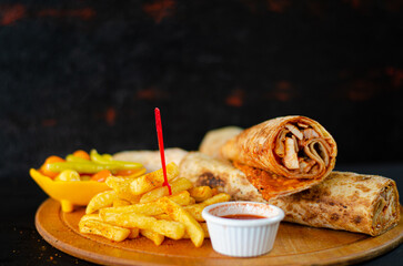 Doner kebab in lavash bread. Close-up delicious chicken doner burrito on black background. Potato chips. selective focus
