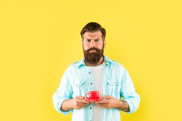 serious unshaven man in shirt with coffee on yellow backdrop, coffee