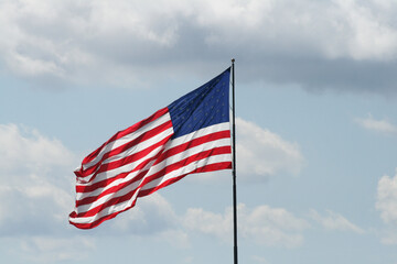 Reverse side of American Flag flying against cloudy sky