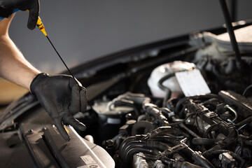 The car mechanic is checking the engine oil level. Overheating of car engine. Motor with open hood....