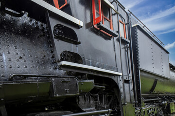 Exterior view of a black steam locomotive, entry ladder, large rivets in black metal, daytime, nobody