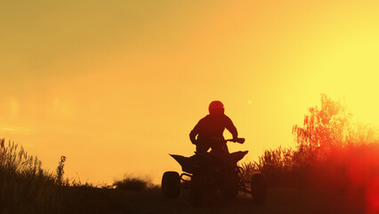Quad biker jumping in sunset.