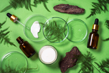 Natural Cosmetic laboratory concept . Glass petri dish with cosmetic products and green plants. Flat lay image.