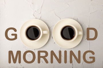 Hot coffee in a white coffee cup on a white marble background with the inscription GOOD MORNING.Concept photo.Design.Hot warming drink concept.Copy space.Top view.Place for text.