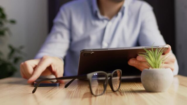 Freelancer works on tablet searching important information for running business on Internet. Self-employed worker checks messages on phone