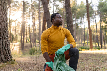 african american man, volunteer collect garbage in the forest, concept of environmentalism care for the environment.