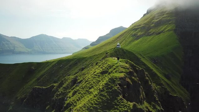 Aerial view of Kalsoy island, Faroe Islands. Amazing Faroese nature, green hills and beautiful rocky cliffs and mountains. Kallur lighthouse. Sunny day in summer. Movie Island in Faroe. 4k footage