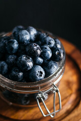 
a jar of blueberries on a wooden board, dark background