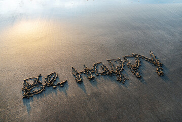 Be happy text written on sand beach