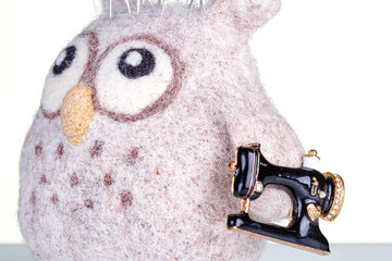 small pillow for needles in the form of an owl and a sewing machine on a white background